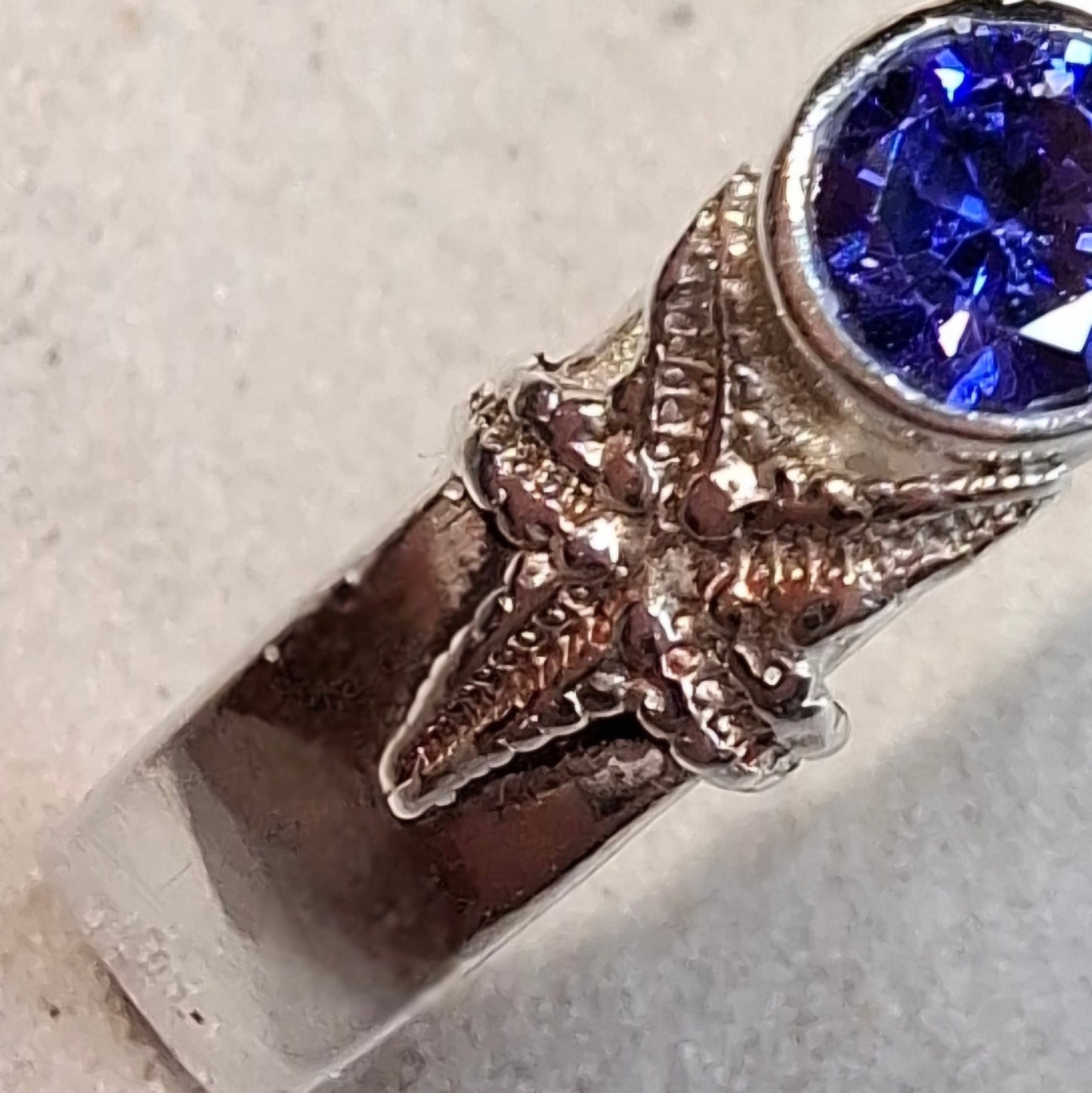 Hammered silver ring featuring a delicate silver starfish and a tanzanite cubic zirconia