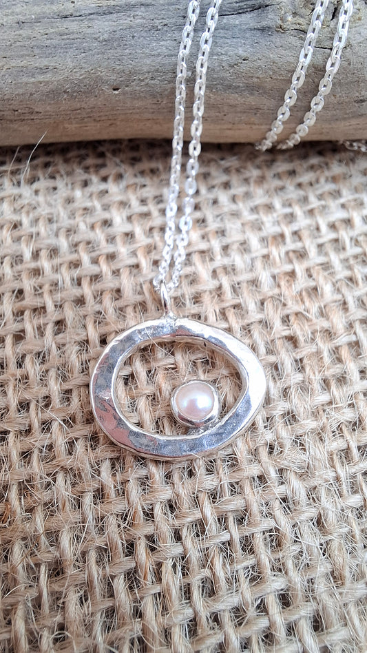 Hammered silver pebble shaped pendant set with a freshwater pearl