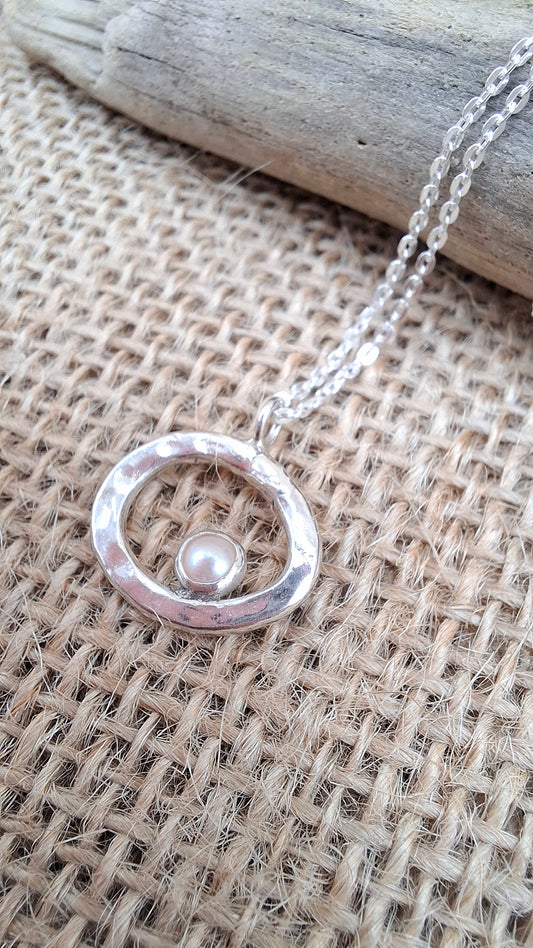 Hammered silver pebble shaped pendant set with a freshwater pearl