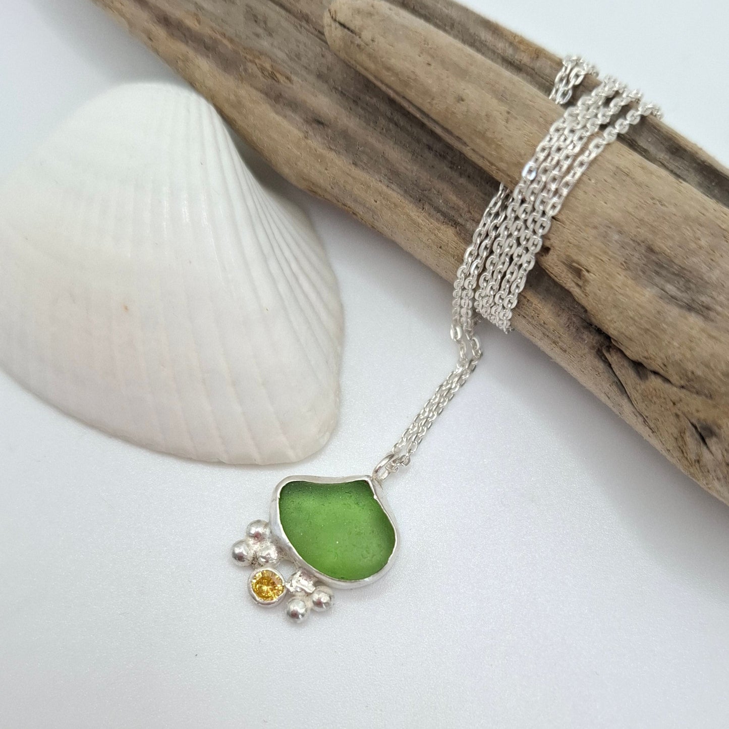 Dinky green seaglass pendant with yellow cubic zirconia charm on a necklace, by Shelley Ide Jewellery, close-up view.
