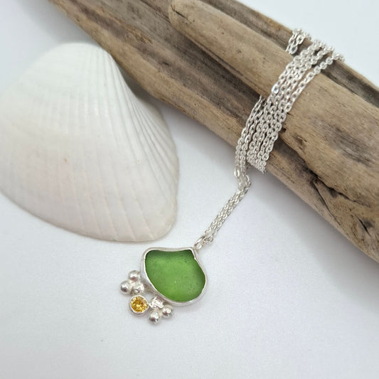 Dinky green seaglass pendant with yellow cubic zirconia charm on a necklace, by Shelley Ide Jewellery, close-up view.