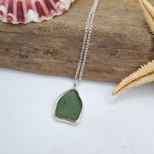 Necklace with a green pendant on a wooden stick with starfish and a shell.