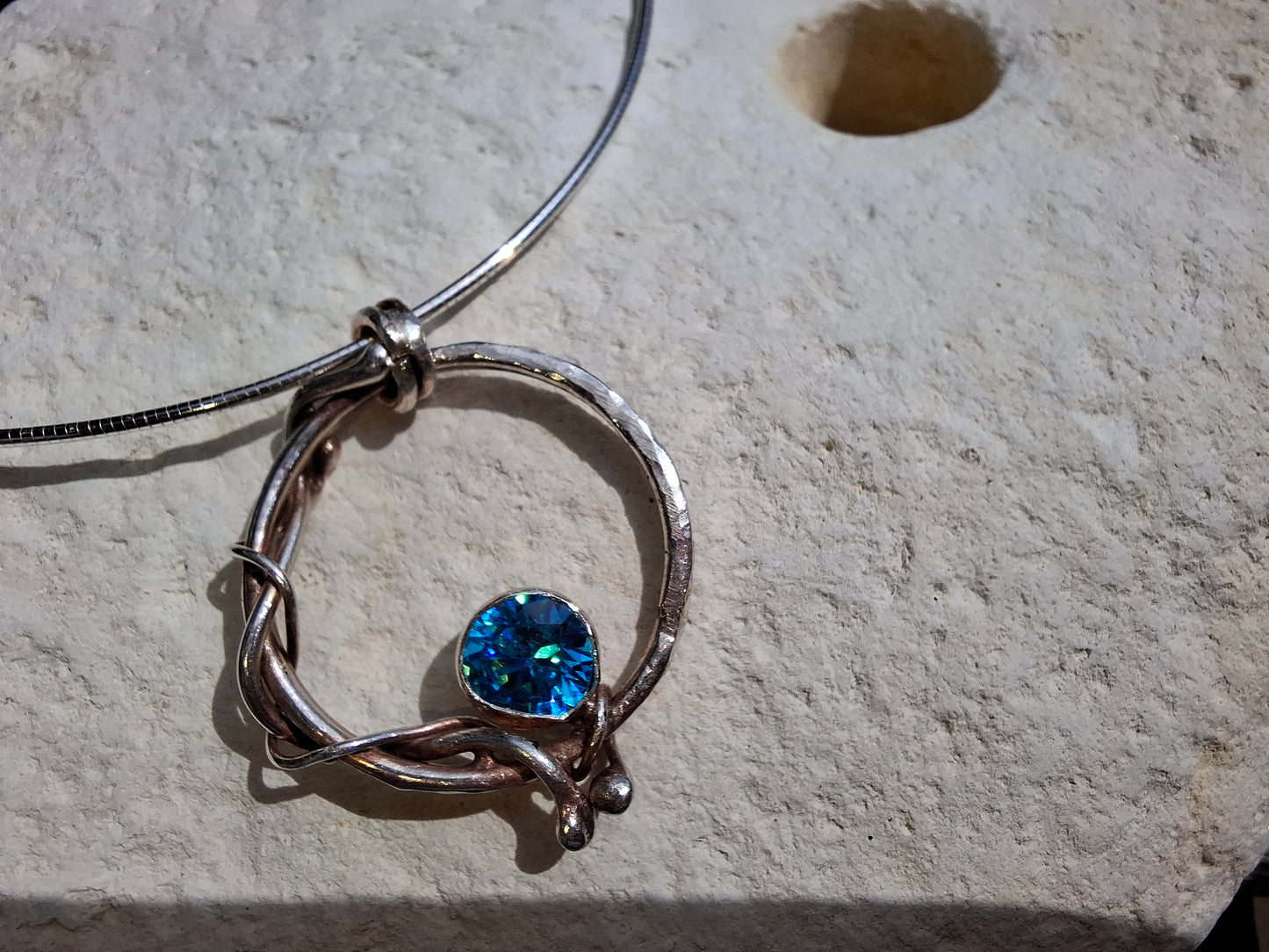 Hammered circle and rope effect pendant with aquamarine cubic zirconia