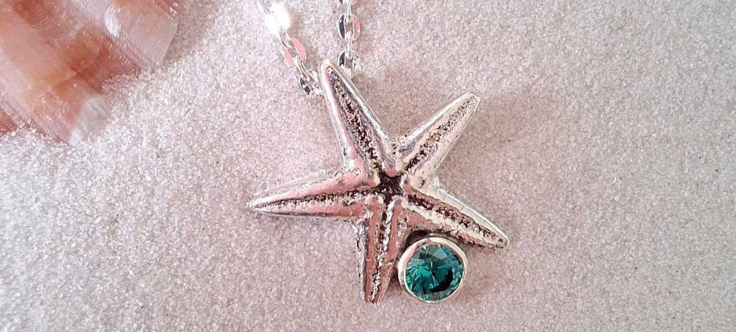 Cast silver starfish pendant with a teal green cubic zirconia, with necklace