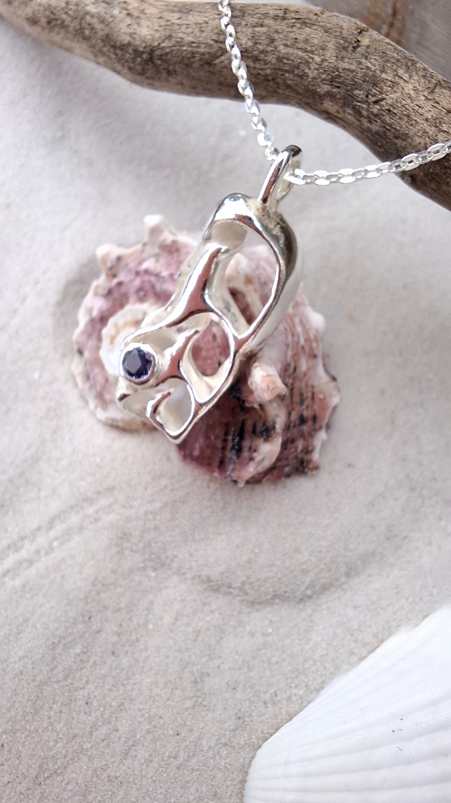 Cast silver seashell pendant with a tanzanite cubic zirconia