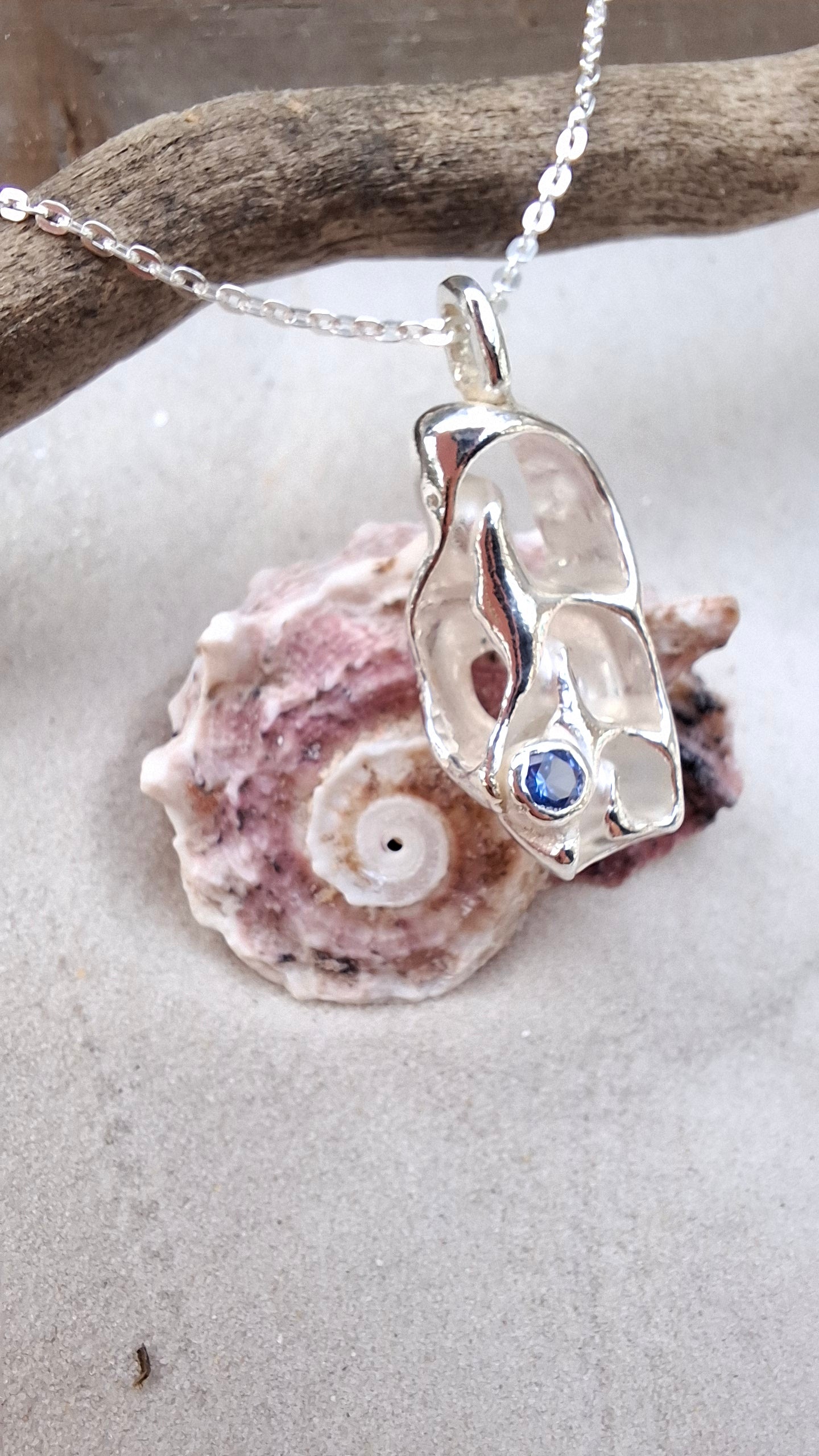 Cast silver seashell pendant with a tanzanite cubic zirconia