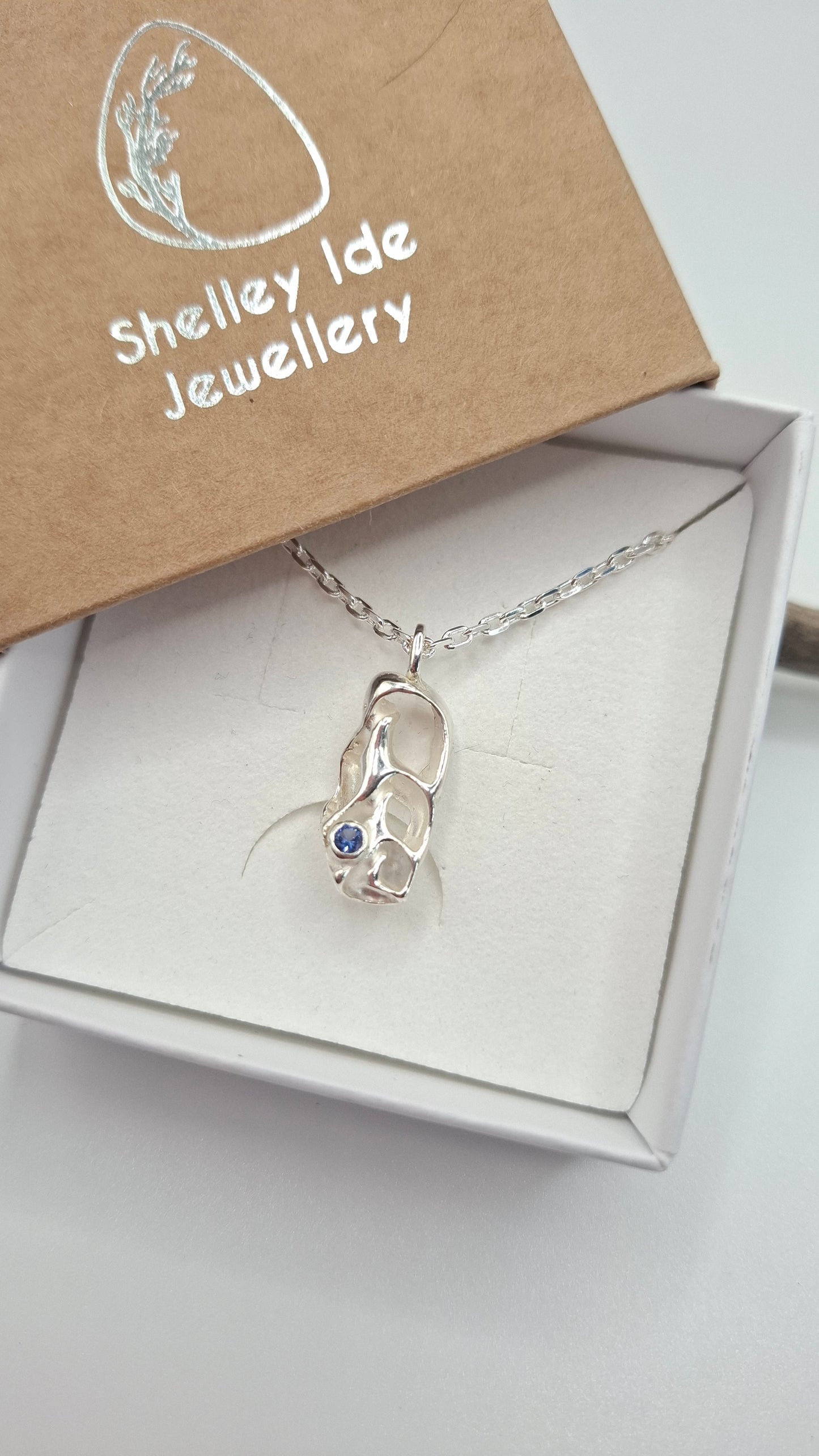 Cast silver seashell pendant with a tanzanite cubic zirconia