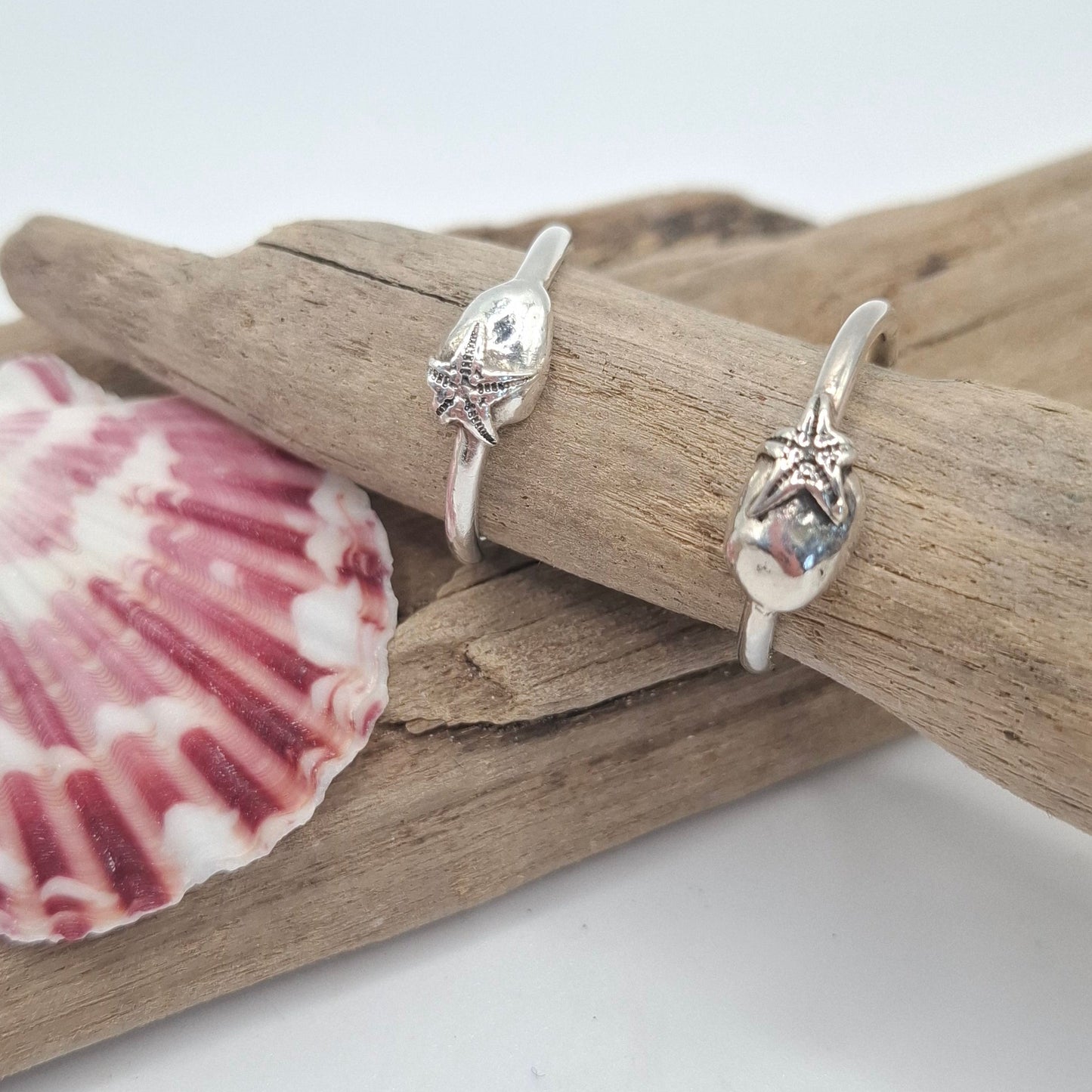 Silver ring featuring a delicate silver starfish hugging a silver pebble | Ocean-Inspired Handmade Jewellery