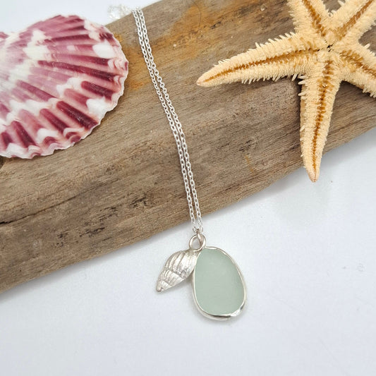 Necklace with a sea glass pendant on a piece of driftwood with a starfish and shell.