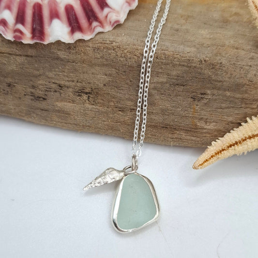 Necklace with a sea glass pendant on a piece of driftwood with shells and a starfish.
