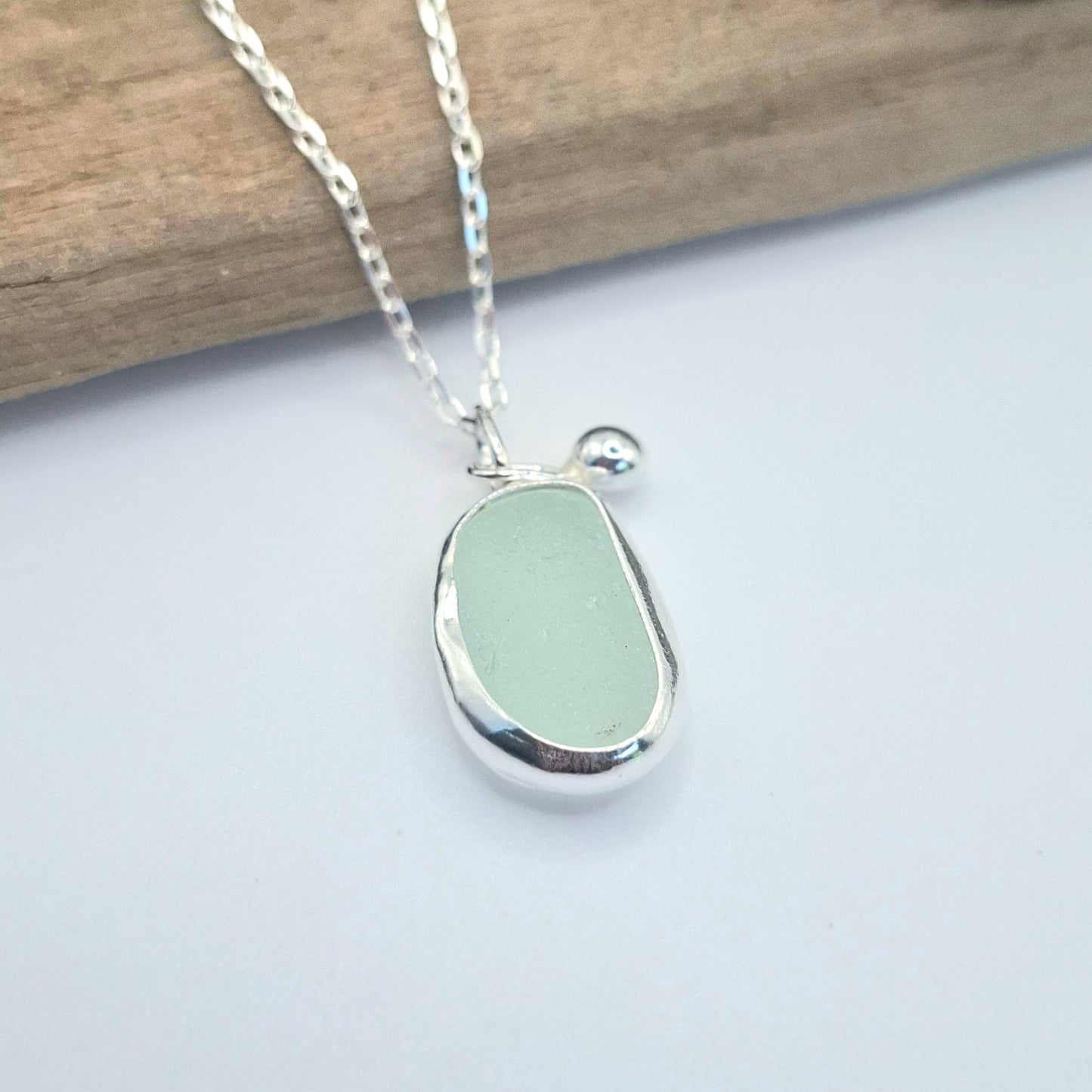 Necklace with a light green seaglass pendant on a white background