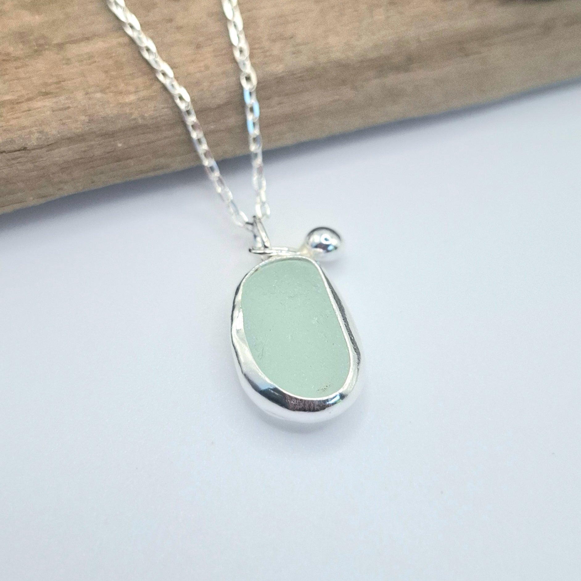 Necklace with a light green seaglass pendant on a white background